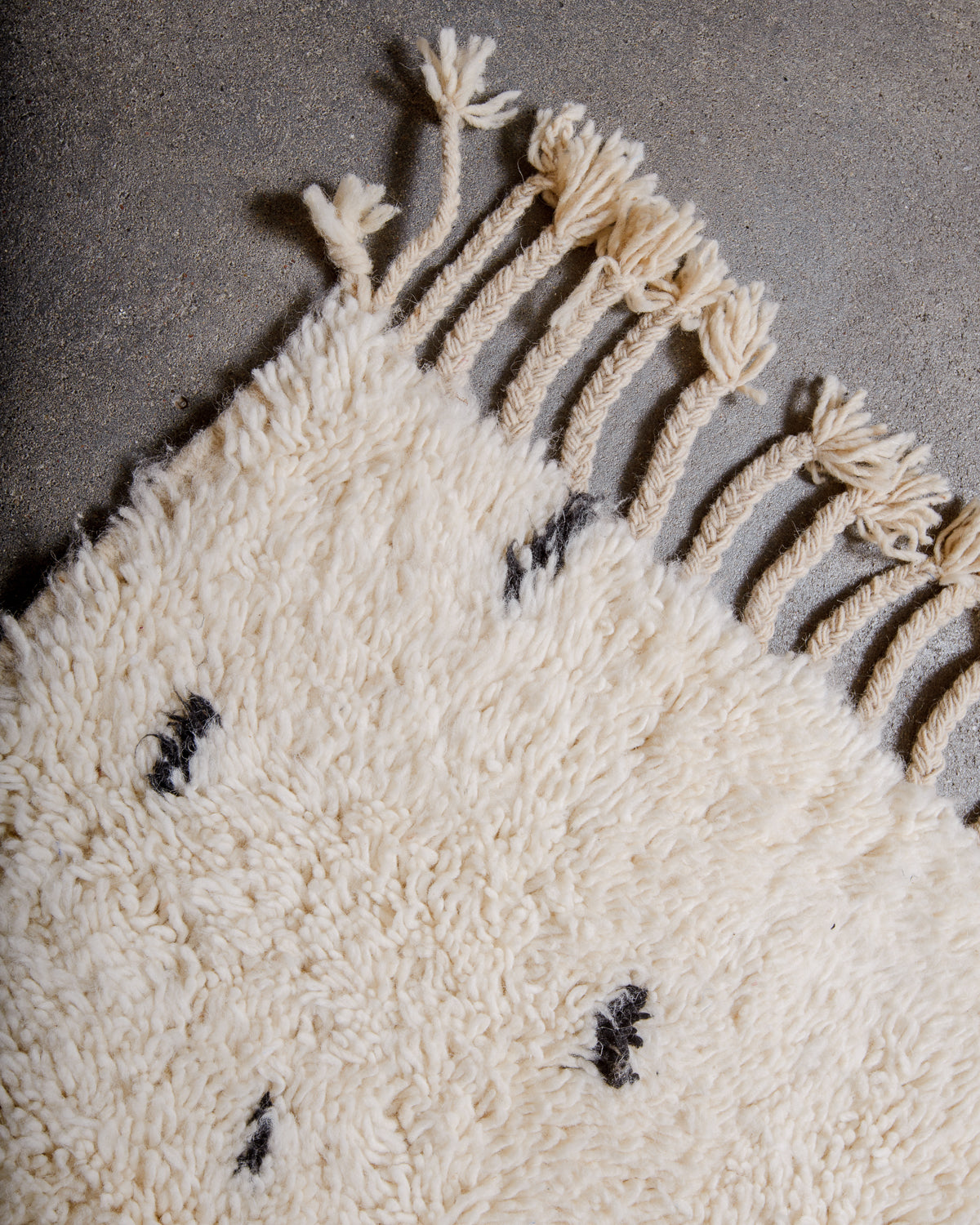 Corner of Berber rug with natural wool tassels across the top.